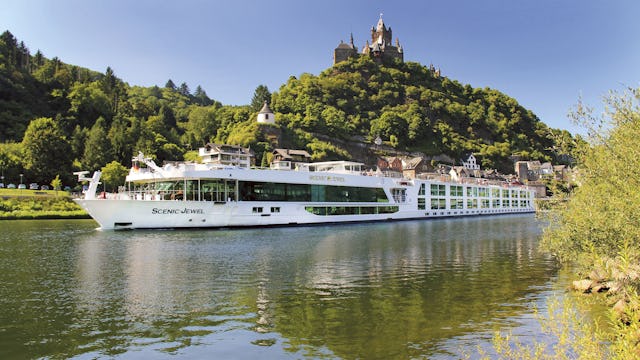 Scenic jokilaiva ja taustalla kukkulan päällä kohoaa linna.